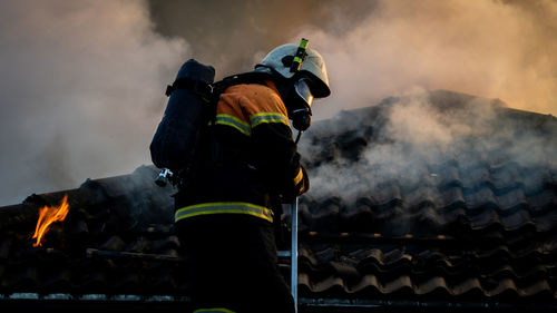 Firefighter spraying water on burning house