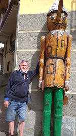 Full length portrait of man standing against building