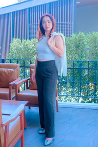 Portrait of smiling young woman standing against railing