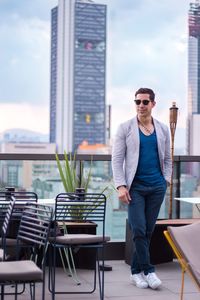 Portrait of young man in city against sky