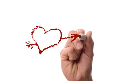 Close-up of hand holding ring over white background