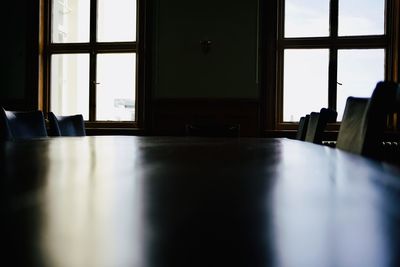 Empty chairs and table against window