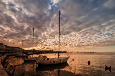 Silhouette boats moored on sea against sky during sunset