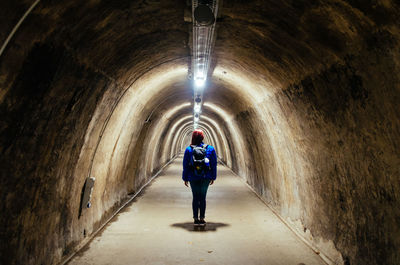 Rear view of woman standing in tunnel