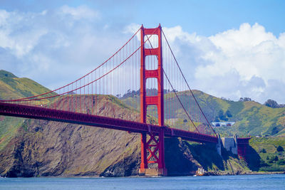 Golden gate bridge over river against cloudy sky