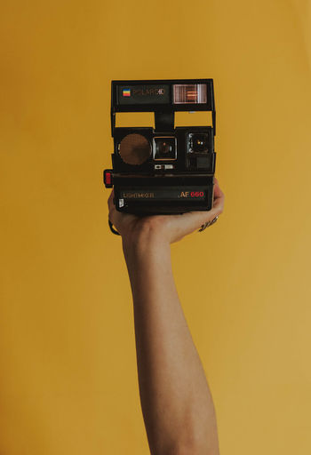 CLOSE-UP OF HAND HOLDING CAMERA