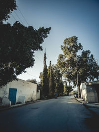 Street amidst trees against clear sky