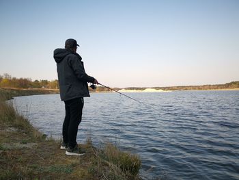 Rear view of man looking at lake against sky