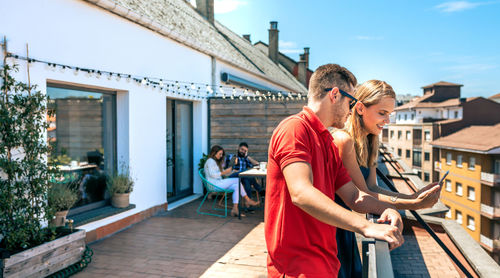 Happy couple looking mobile in work pause in office rooftop on a summer day