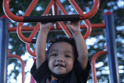 Portrait of girl hanging on monkey bars