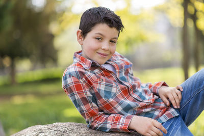 Portrait of boy smiling while sitting at park