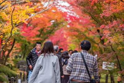 Rear view of people walking on autumn leaves