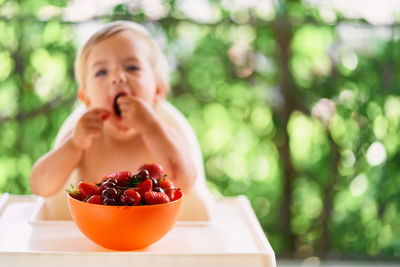 Baby girl sitting while eating strawberry at home