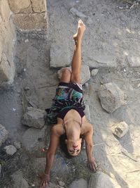 High angle view of seductive woman stretching on stone at field