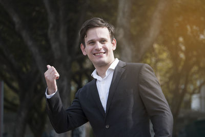 Portrait of businessman gesturing on sunny day