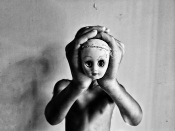 Portrait of shirtless boy standing against wall