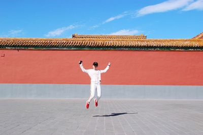 Young woman jumping against temple during sunny day