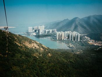 High angle view of buildings and lake against mountains and sky on sunny day
