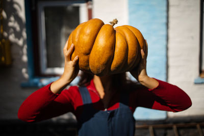 Girl holds big pumpkin on head