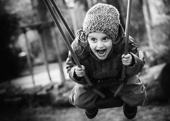 Portrait of smiling girl holding swing in playground
