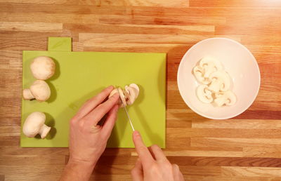 Directly above shot of woman cutting mushrooms at table