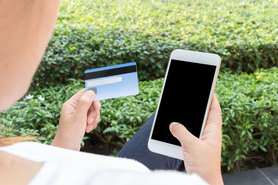 Midsection of man using mobile phone in park