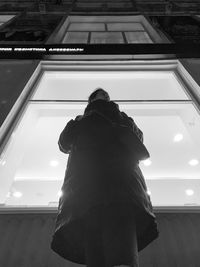 Low angle view of woman looking through window