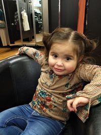 Portrait of cute girl sitting on sofa at home