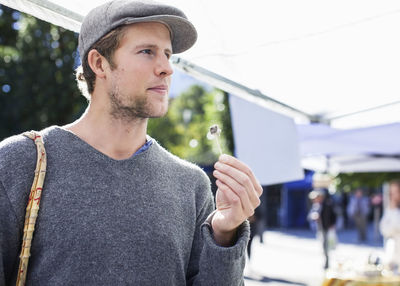 Thoughtful man eating with toothpick at market