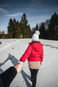 Rear view of woman walking on snow against trees