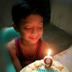 Innocent boy looking at birthday cake in room