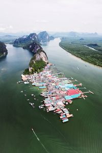 High angle view of fishing village on sea by mountains against sky