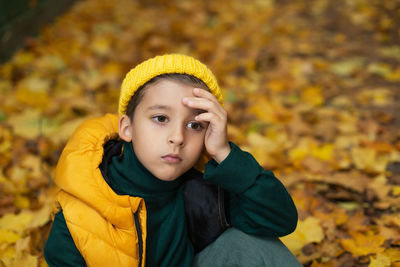 Portrait of young woman standing against yellow flower