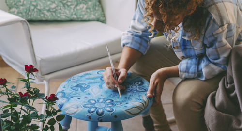 Midsection of woman painting on stool