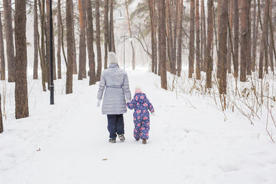 Rear view of woman walking on snow covered land