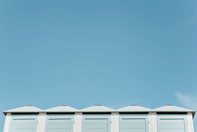 Low angle view of beach huts against clear blue sky