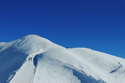 Low angle view of snowcapped mountain against clear blue sky