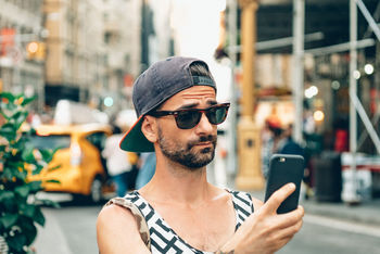 Man taking selfie through smart phone in city