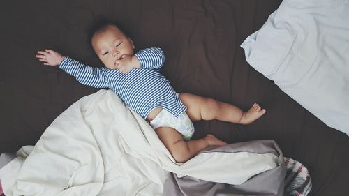 High angle view of baby boy lying on bed at home