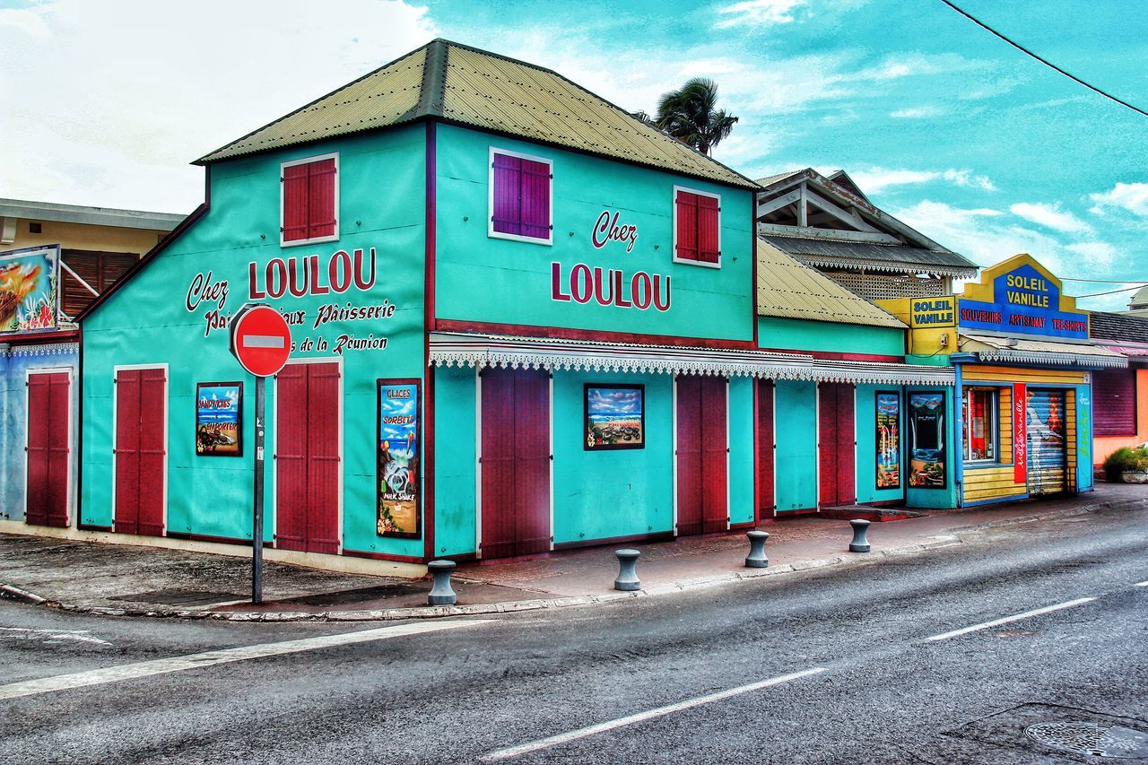 architecture, building exterior, built structure, road, sky, text, street, western script, transportation, communication, the way forward, day, graffiti, outdoors, road sign, multi colored, house, no people, cloud - sky, guidance