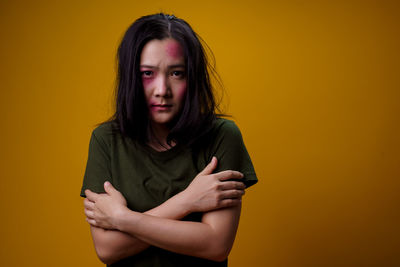 Portrait of beautiful young woman against yellow background