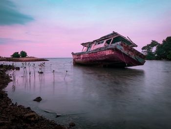 Abandoned boat in water against sky