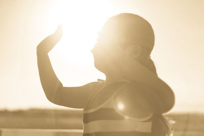 Close-up of girl gesturing against sky on sunny day