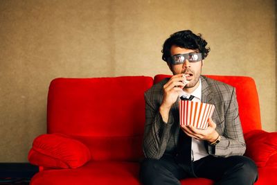 Young man looking away while sitting on sofa