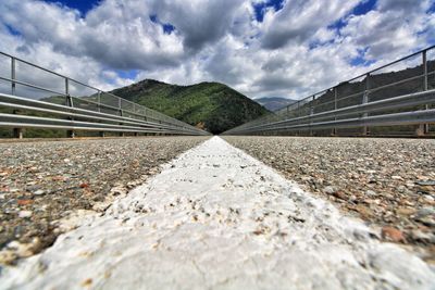 Surface level view of footbridge against cloudy sky