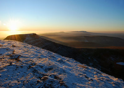 Scenic view of snowcapped mountains against clear sky during sunset