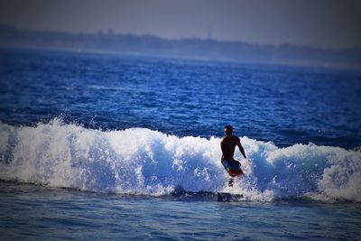 Man surfing in sea against clear sky