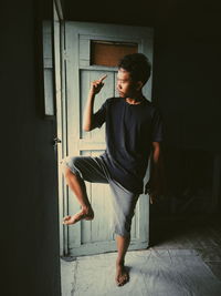 Young man standing at entrance of house