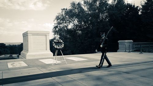 Man walking by building in city against sky