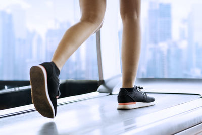 Low section of woman running on treadmill at gym